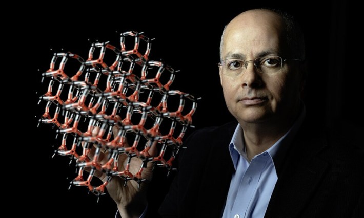 A photo of Omar Yaghi holding a ball and stick model of metal organic framework.