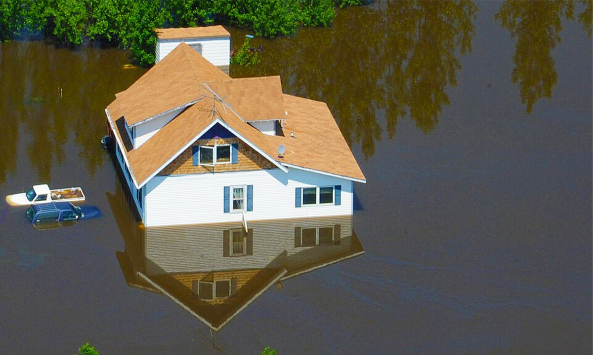 An aerial photo of a house nearly completely underwater from a flood.